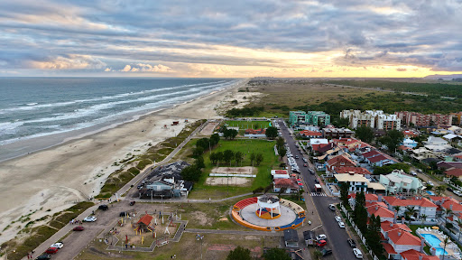 Paisagem aérea de Capão Novo ao pôr do sol, com mar e construções